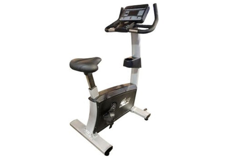 Upright exercise bike with black and gray frame, padded seat, handlebar console display, and silver base on white background