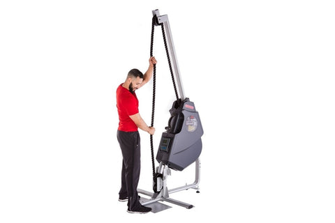Man in red shirt using gray and black rope training machine with pulley system on white background