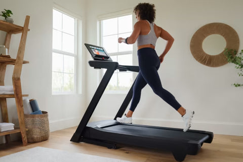 Black NordicTrack EXP 14i treadmill with digital console displaying workout content, on white background