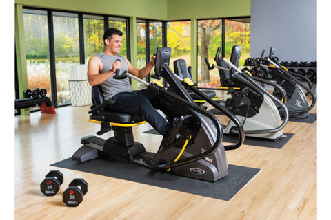 Black and yellow NuStep T6PRO recumbent elliptical stepper with padded seat, handlebars, and digital display on white backgro
