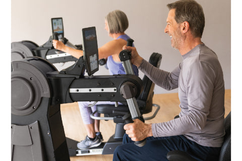 NuStep UE8MAX upper body ergometer with black and gray frame, padded black seat, dual handles, and tablet holder displaying w