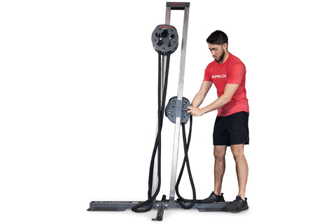 Man in red shirt using gray and black upright rope trainer with dual handles on white background