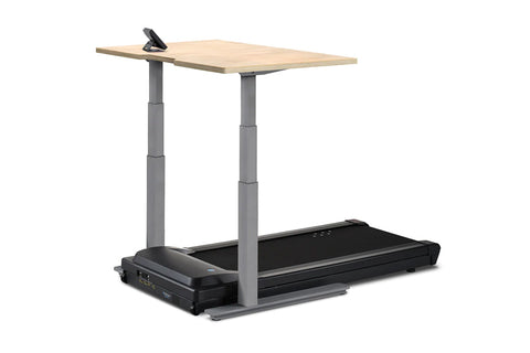Height-adjustable desk treadmill with light wood top, gray steel frame, and black motorized treadmill base on white backgroun