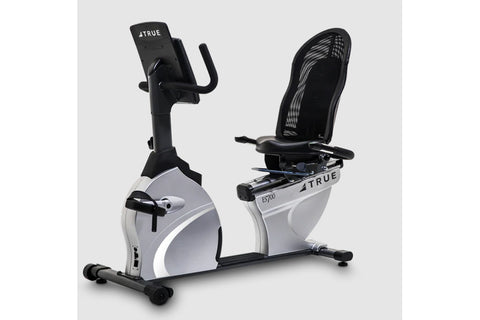 TRUE ES700 recumbent exercise bike with white and black frame, mesh backrest, and digital console on gray background