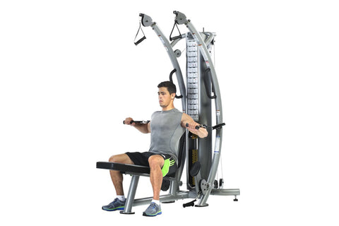 Man using gray and black functional trainer with dual cable systems and weight stack, seated position