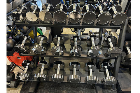 Three-tier black dumbbell rack holding chrome dumbbells ranging from 5 to 50 pounds, displayed against white background