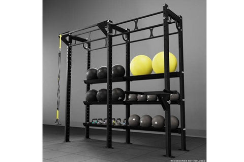 Black steel functional training rig with pull-up bar, storage shelves displaying yellow and black medicine balls and weighted