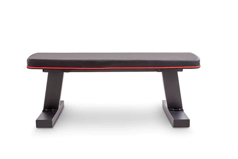 Black and red flat weight bench with padded seat, adjustable backrest, and sturdy black metal frame on white background