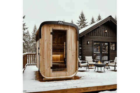 Cedar wood sauna with black metal roof and glass door, featuring interior benches and heater, on white background