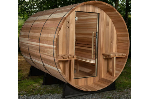 Cylindrical wooden barrel sauna with cedar construction, open door, built-in benches, and black metal support frame on white 