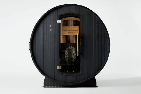 Black wood barrel sauna with glass door, brass handles, and metal bands, viewed on white background
