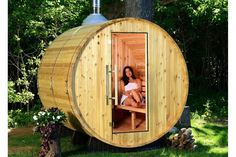 Cylindrical wooden barrel sauna with natural pine exterior, open glass door showing cedar bench interior, metal hinges and ha