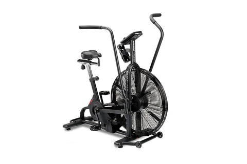 Black upright stationary air bike with large fan wheel, padded seat, dual handlebars, and digital display on white background