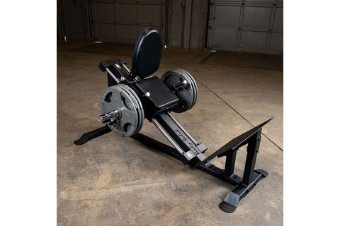 Black and silver compact leg press and hack squat machine with padded seat, footplate, and circular backrest on white backgro