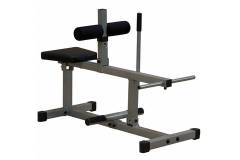 Seated calf raise machine with gray steel frame, black padded seat, cylindrical leg rest, and foot platform on white backgrou