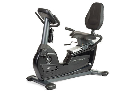 BodyCraft R200 semi-recumbent exercise bike with black seat, gray frame, digital console, and foot pedals on white background
