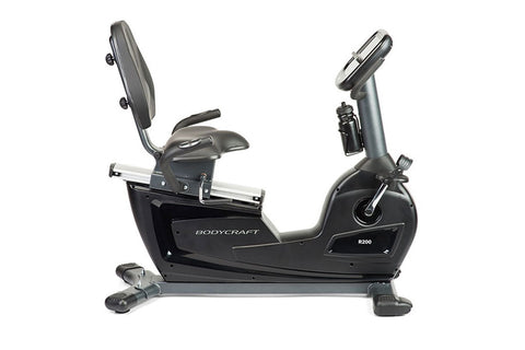 BodyCraft R200 semi-recumbent exercise bike with black seat, gray frame, digital console, and foot pedals on white background