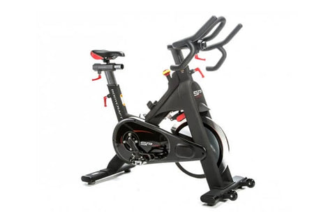 Black indoor training cycle with red accents, dual handles, red seat, and fixed wheelbase on white background