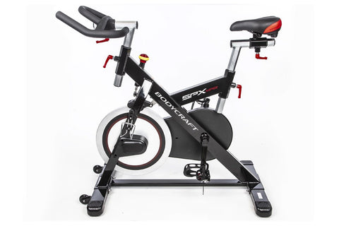 Black and red indoor training cycle with curved handlebars, padded seat, and stabilizer base on white background
