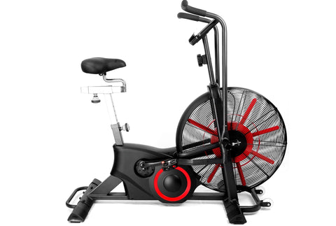 Black and red air exercise bike with large fan wheel, upright handlebars, padded seat, and digital display on white backgroun