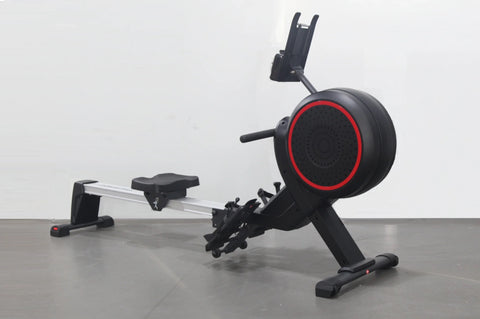 Black and red stationary rowing machine with aluminum rail, adjustable seat, foot pedals, and phone holder on white backgroun