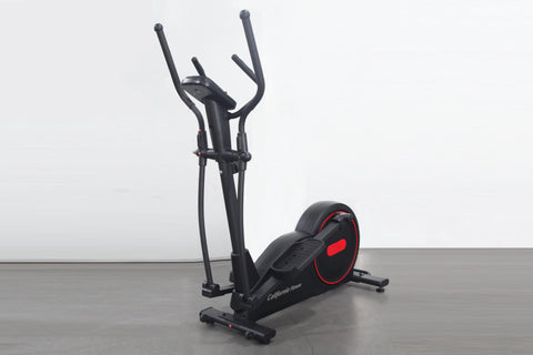 Black and red elliptical cross-trainer with dual handles and foot pedals on gray floor, white background