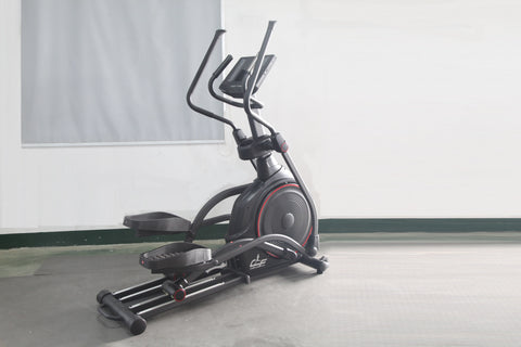 Black and gray stationary elliptical trainer with red accent trim and dual handle bars, displayed on concrete floor