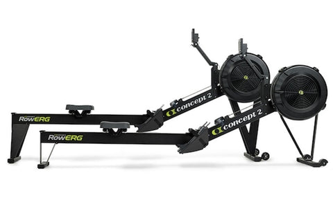 Black Concept2 RowErg indoor rowing machine with dual black resistance fans, extended arm, and stabilizing legs on white back
