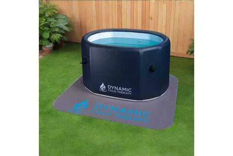 Dark navy inflatable cold plunge tub with turquoise water visible through clear top panel, sitting on gray mat with blue Dyna