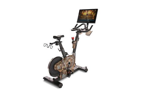 Black and red stationary exercise bike with tablet holder displaying workout screen, on white background