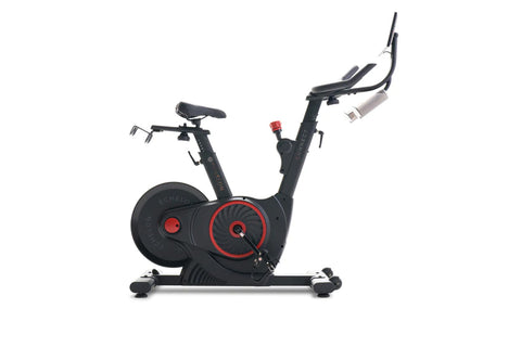 Black and red indoor stationary exercise bike with dual handlebar options and weighted flywheel on white background