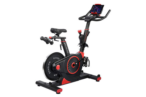 Black and red stationary exercise bike with digital display, adjustable handlebars, and foot pedals on white background