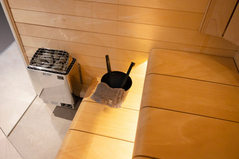 Harvia KIP white electric sauna heater with black interior, metal stone basket, and dial controls on white background
