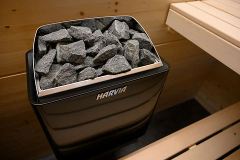 Harvia KIP electric sauna heater with black steel body, stainless steel top basket filled with gray sauna stones, and white b