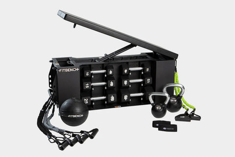 Black FITBENCH ONE weight bench with hinged storage top, dumbbell set, kettlebells, resistance bands, and suspension trainer 