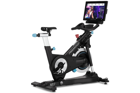 Freemotion CoachBike indoor exercise bike with black frame, blue accents, touchscreen display mounted on handlebar, and silve