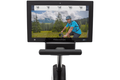 Black Freemotion r22.9 recumbent exercise bike with mesh backrest, foot pedals, and attached digital display screen showing w