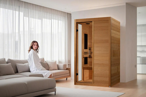 Cedar wood sauna with two tinted glass doors and black interior benches, featuring ventilation vents and metal handles, on wh