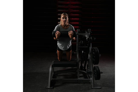 Hammer Strength plate-loaded leg press machine with black handles, seat, and weight plates on white background