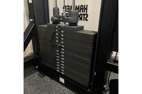 Black cable machine with dual pulldown and row stations, adjustable seat, and weight stack on white background