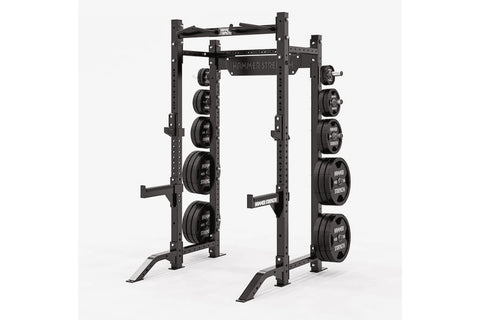 Black Hammer Strength HD Athletic NX half rack with weight plates mounted on both sides, open frame design on white backgroun