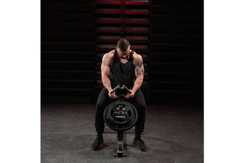 Black plate-loaded gripper machine with padded seat, curved handles, and iron grip weight plate loaded on white background