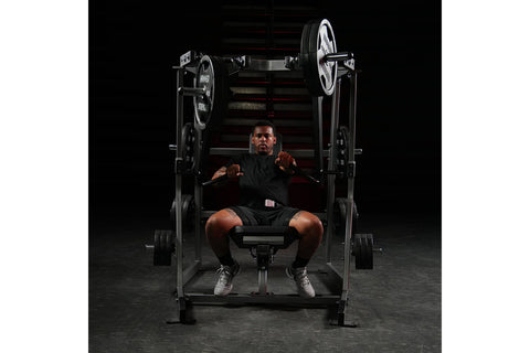 Black plate-loaded decline chest press machine with adjustable iso-lateral arms, padded seat, and chrome handles on white bac