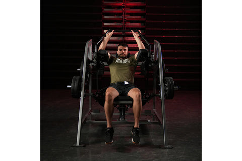 Black plate-loaded pullover machine with padded seat and backrest, metal frame, and dual handles on white background