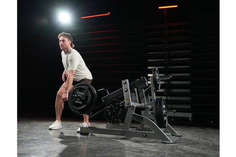 Hammer Strength plate-loaded squat high pull machine with gray steel frame, black handles, and weight plate pegs, on white ba