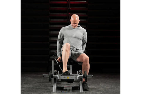 Black Hammer Strength plate-loaded tibia dorsi flexion machine with metal frame, foot platform, and adjustment handles on whi