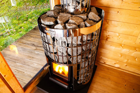 Harvia Cilindro 16 wood-burning sauna stove heater with stainless steel grid cage, black firebox with visible flames, and gra