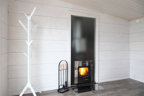Black wood-burning stove with active flames in white aluminum frame fireplace insert, displayed in modern white shiplap room 
