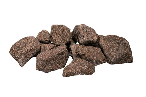 Pile of brown granite sauna stones with rough textured surface on white background