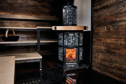 Harvia Legend 240 cylindrical black wood-burning sauna stove with lit fire visible through glass door and gray soapstone exte